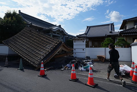 A man helps clean the damaged gate of Jofukuji Buddhist temple in Kumamoto, southwestern Japan, Wednesday, July 29, 2026, the day after an earthquake hit the area. 