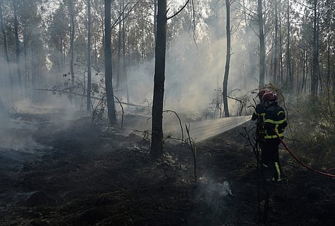 Firefighters hose down a smoldering fire in Blagon, during wildfires in southwestern France, Wednesday, July 29, 2026. 