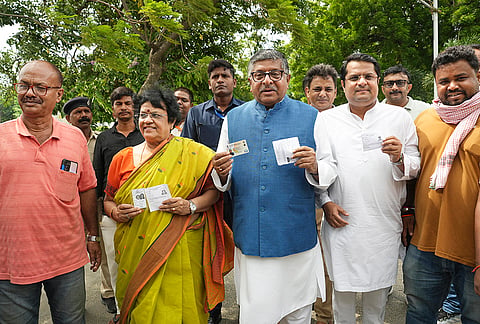BJP MP Rabishankar Prasad along with his family shows their voter identity cards during the Bankipur Assembly by-election, in Patna.