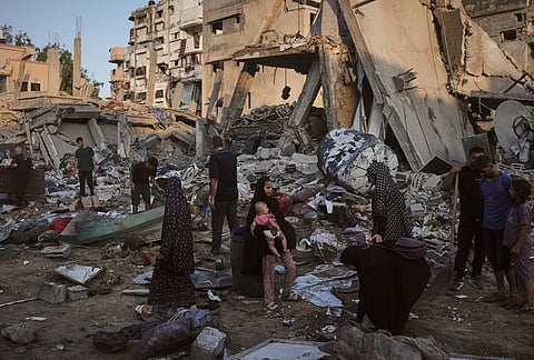 Palestinians salvage their belongings from the rubble of a building and tents destroyed in an Israeli airstrike in Gaza City.