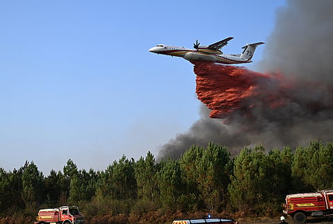 A De Havilland Canada Dash 8-400 releases fire retardant as it flies over a forest near Blagon, during wildfires in southwestern France, Wednesday, July 29, 2026. 