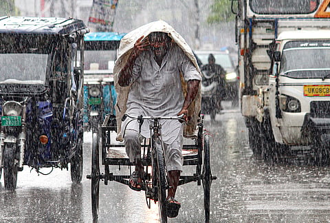 A commuter covers himself amid rainfall, in Haridwar, Uttarakhand.