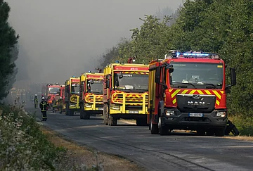 | Photo: AP/Baz Ratner : Firefighters engines are lined along the road as they fight a fire in a forest near Blagon, during wildfires in southwestern France, Wednesday, July 29, 2026.