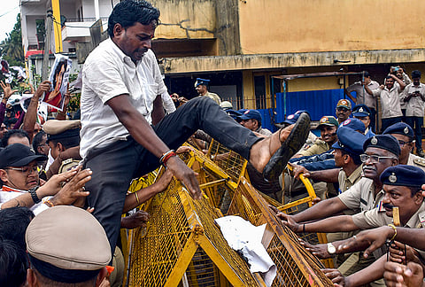 BJP Yuva Morcha workers scale the barricades during a protest and lay a seige to the Congress office condemning the alleged remarks made by Congress MP Priyanka Gandhi on Union Minister Pralhad Joshi, in Hubballi-Dharwad district, Karnataka.