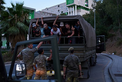 Migrants who crossed into Spain are escorted by Spanish soldiers towards the Spanish-Moroccan border for their return to Morocco from the Spanish enclave of Ceuta, Sunday, Aug. 2, 2026. 