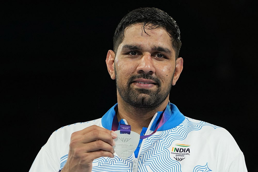 India's Narender Berwal, silver medalist, celebrates on the podium of the men's 90kg boxing final at the Commonwealth Games in Glasgow, Scotland. - | Photo: AP/Eranga Jayawardena