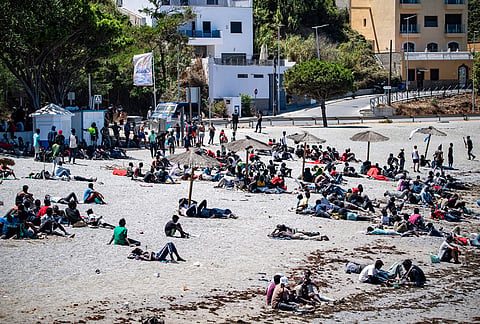 Migrants who crossed into Spain from Morocco gather on a beach in the Spanish enclave of Ceuta, Sunday, Aug. 2, 2026.
