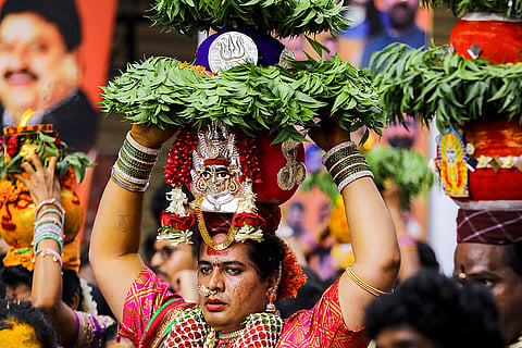 A member of the LGBTQ+ community and others carry 'Bonam', a pot filled with cooked rice, during the 'Ashada Masam Bonalu' festival celebration, at the Golconda Fort, in Secunderabad, near Hyderabad, Telangana.