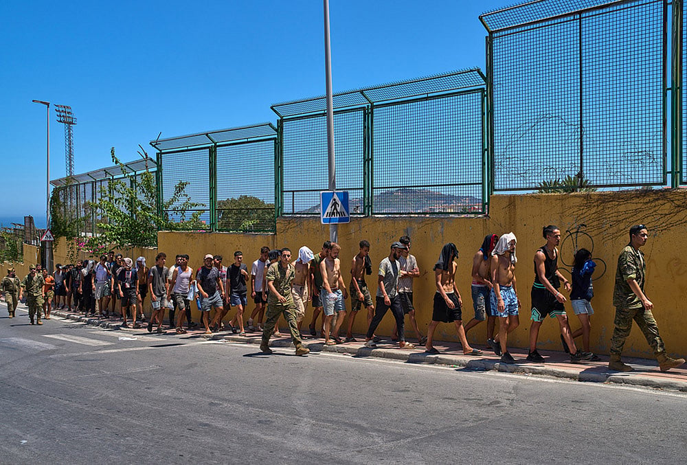 Migrants who crossed into Spain are escorted by Spanish soldiers toward the Spanish-Moroccan border for their return to Morocco from the Spanish enclave of Ceuta, Sunday, Aug. 2, 2026.  - | Photo: AP/Bernat Armangue