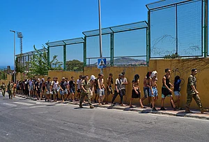 | Photo: AP/Bernat Armangue : Migrants who crossed into Spain are escorted by Spanish soldiers toward the Spanish-Moroccan border for their return to Morocco from the Spanish enclave of Ceuta, Sunday, Aug. 2, 2026.