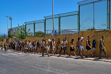 | Photo: AP/Bernat Armangue : Migrants who crossed into Spain are escorted by Spanish soldiers toward the Spanish-Moroccan border for their return to Morocco from the Spanish enclave of Ceuta, Sunday, Aug. 2, 2026.