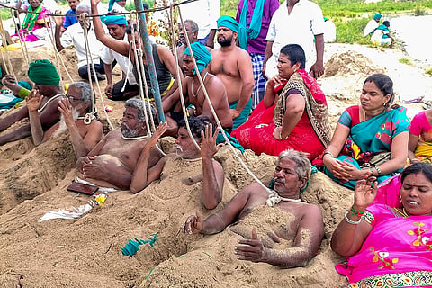 Farmers partially bury themselves under the soil of the Cauvery river while tying a rope around their necks during a protest, led by National South Indian Rivers Inter-linking Farmers Association President P Ayyakannu, against the DK Shivakumar-led Karnataka government and the central government over the Cauvery issue, in Tiruchirappalli, Tamil Nadu.