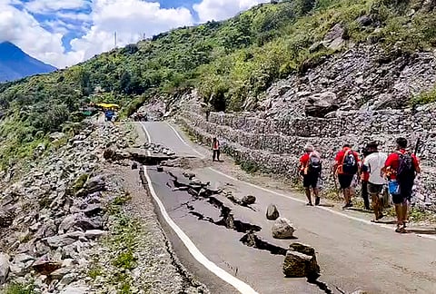 'Kanwariyas' walk past a damaged portion of a road along the Gangotri Highway (NH 34), amid the ongoing 'Kanwar Yatra', near Bhatwari, in Uttarkashi district, Uttarakhand.