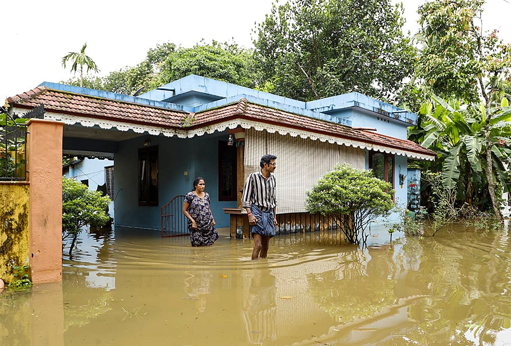 Residents wade through floodwaters outside their inundated homes after incessant monsoon rains caused widespread flooding, at Ranni, in Pathanamthitta district of Kerala, Monday, Aug. 3, 2026.  - | Photo: PTI
