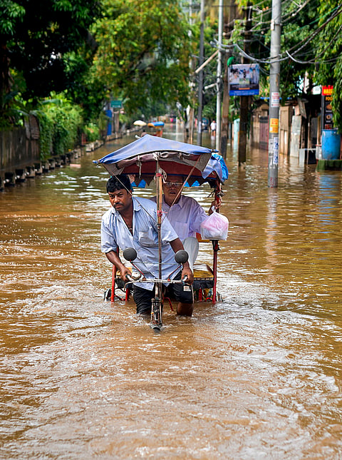 A rickshaw puller wades through a waterlogged road following heavy rainfall, in Guwahati, Assam.