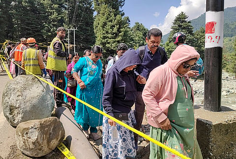 Security and rescue personnel assist stranded tourists as they navigate a damaged stretch following a cloudburst that washed away a bridge at Langanbal, in Pahalgam, Anantnag district.