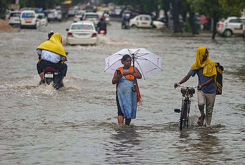 Commuters make their way through a waterlogged road during monsoon rain, in Prayagraj, Uttar Pradesh.