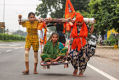 Devotee Aarti, right, carries her mother-in-law, Usha, on a shoulder-borne seat as they return after collecting holy Ganga water from Haridwar during the Kanwar Yatra, in Meerut, Tuesday, July 28, 2026. Aarti, accompanied by her family, is undertaking the pilgrimage while carrying her mother-in-law in a gesture of devotion and care. 