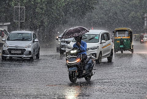 A commuter covers himself during rainfall, near Connaught Place, in New Delhi. 