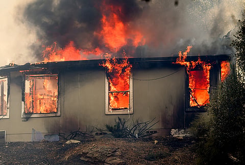 Flames consume a home as the Gann Fire burns near Copperopolis on Tuesday, Aug. 4, 2026, in Calaveras County, California. 