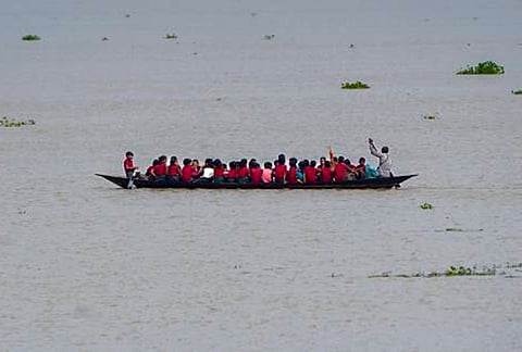 Students travel to school in a country boat after floodwaters submerge roads, in Morigaon district, Assam.