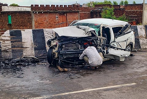 A man sits near a wreckage of a car after it crashed into a divider, in Jhansi, Uttar Pradesh. Aban Ahmad, the youngest son of slain gangster-turned-politician Atiq Ahmad, and his friend were killed. 