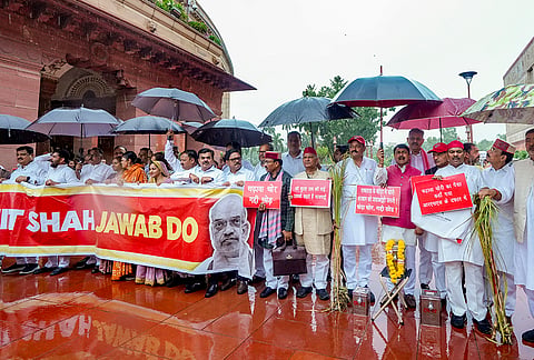 Samajwadi Party MP Anand Bhadauria, Congress MP Sanjna Jatav and other opposition MPs stage a protest over the alleged embezzlement of donations at Ayodhya’s Shri Ram Janmbhoomi Temple during the ongoing Monsoon session of Parliament, amid rainfall, in New Delhi.
