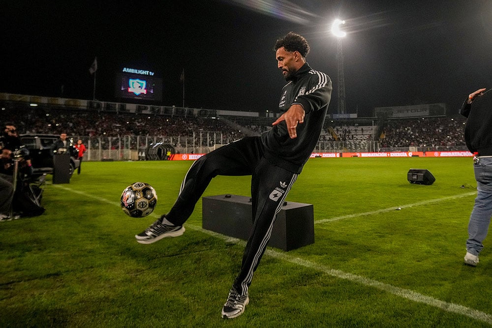Cape Verde goalkeeper Vozinha kicks a soccer ball to Colo Colo supporters at his welcoming event at the Monumental Stadium in Santiago, Chile. - | Photo: AP/Esteban Felix