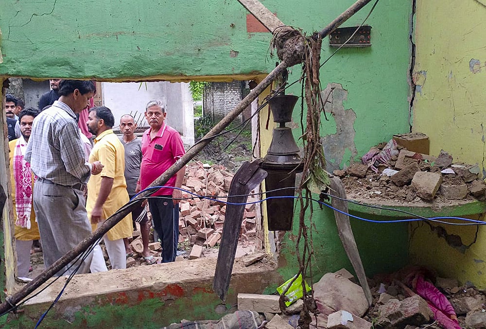 | Photo: PTI : People gather after a portion of a dilapidated house collapsed, killing six people, in Mahuli village of Pratapgarh district, Uttar Pradesh.
