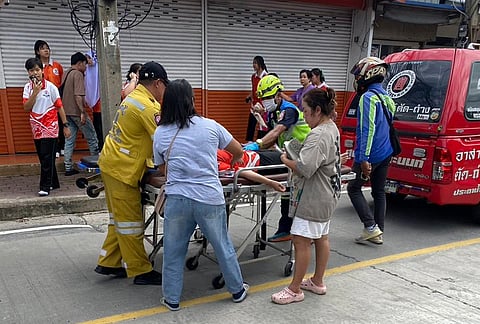 An injured is carried on a stretcher outside a school where deaths and injuries were reported after a shooting in Thailand's Nonthaburi province, Friday, Aug. 7, 2026. 