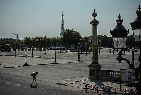 A person walks with an umbrella on Place de la Concorde in Paris during a heat wave, Wednesday, July 29, 2026. 