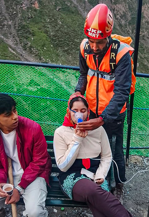 A member of Jammu and Kashmir Police's Mountain Rescue Team (MRT) assists a pilgrim during the annual Amarnath Yatra, on the Baltal route, in Ganderbal district.