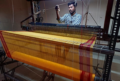 A weaver operates a traditional loom while weaving a fabric on the occasion National Handloom Day, in Bastar district, Chhattisgarh.
