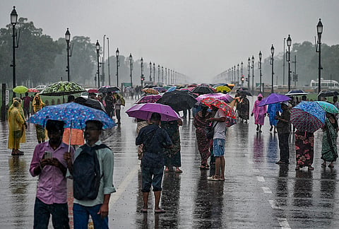People walk at the Kartavya Path amid rainfall, in New Delhi.