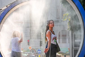 | Photo: AP/Vadim Ghirda : A woman pauses while she walks through a water mist machine installed by city administration to assist people in coping with the heat, as the National Weather forecaster issued an extreme heat code red warning for most parts of the country, in Bucharest, Romania, Thursday, Aug. 6, 2026.