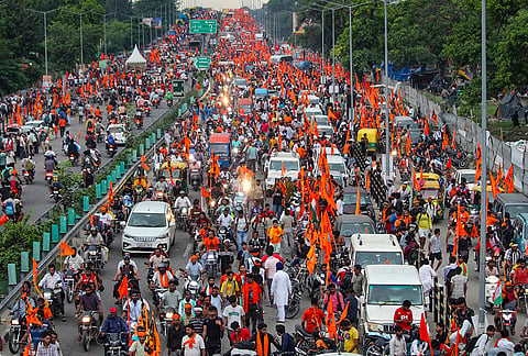 ‘Kanwariyas’ carrying saffron flags move along a road amid heavy traffic ahead of the conclusion of the ‘Kanwar Yatra’ procession on the Delhi-Haridwar Expressway, in Haridwar, Uttarakhand.