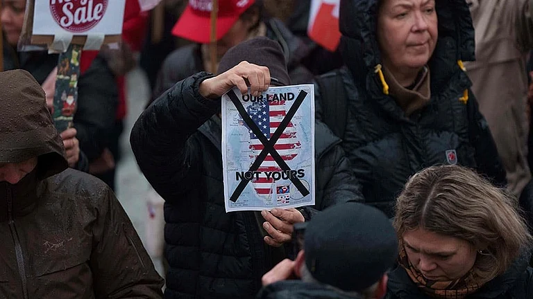 A man holds a map of Greenland covered in the American flag crossed out with an X during a protest against Trump's policy towards Greenland in front of the US consulate in Nuuk, Greenland. - | Photo: AP/Evgeniy Maloletka