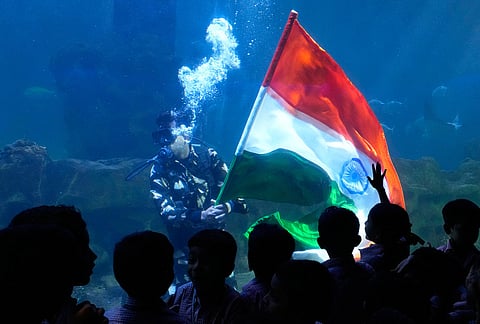 Schoolchildren watch as a scuba diver displays the Indian flag at a marine aquarium on the eve of Independence Day in Chennai.