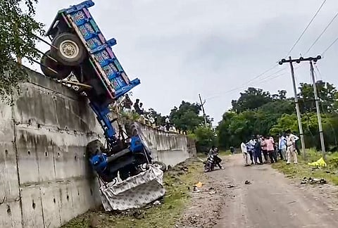 People gather as they look on the wreckage of a tractor trolley carrying Kanwariyas fell off a bridge, in Dhar district, Madhya Pradesh. 