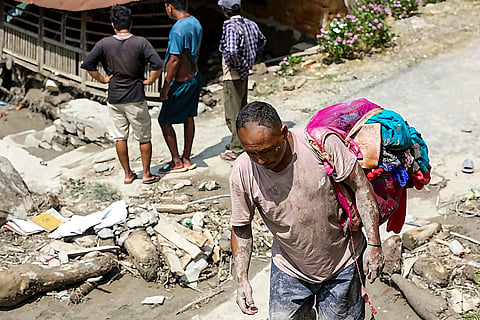 A man moves with his belongings at the flood affected Benighat area, in Dhading district, Nepal.
