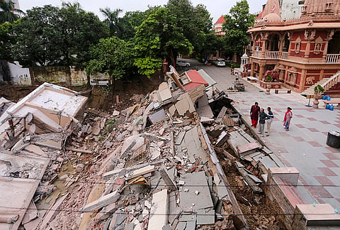 People look at the debris after a portion of the Swaminarayan temple premises collapsed into a deep crater caused by heavy rainfall, in Prayagraj, Uttar Pradesh.