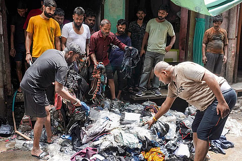 People sort through burnt clothes after a major fire broke out at a garment shop in Gandhi Nagar area, in New Delhi.