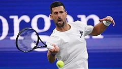 Novak Djokovic, of Serbia, returns the ball during a practice session with Denis Shapovalov, of Canada, at the U.S. Open tennis championships Thursday. - Frank Franklin II/AP Photo