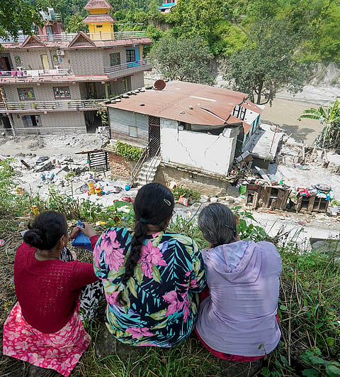 People sit on higher ground near their damaged houses in the aftermath of the recent flash floods, in Galchhi, Dhading district, Nepal, Sunday, Aug. 30, 2026. 