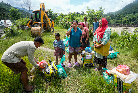 People receive relief material distributed by the administration in the aftermath of the recent flash floods, in Galchhi, Dhading district, Nepal, Sunday, Aug. 30, 2026. 