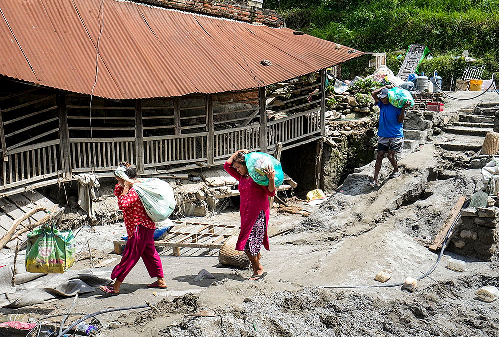 People carrying relief material move to a safer place in the aftermath of the recent flash floods, in Galchhi, Dhading district, Nepal, Sunday, Aug. 30, 2026.  - | Photo: PTI/Nand Kumar