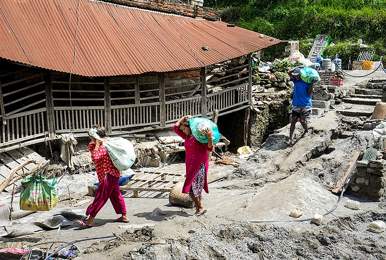 People carrying relief material move to a safer place in the aftermath of the recent flash floods, in Galchhi, Dhading district, Nepal, Sunday, Aug. 30, 2026. - | Photo: PTI/Nand Kumar