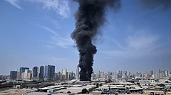 A black plume of smoke rises from a warehouse at the industrial area of Sharjah City in the United Arab Emirates following reports of Iranian strikes in Dubai, United Arab Emirates, Sunday, March 1, 2026. - Altaf Qadri; AP