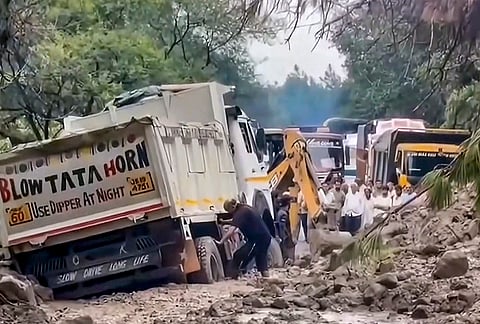 People gather as an excavator removes mud and debris after a road was blocked following a landslide, in Samba, Jammu and Kashmir, Sunday, Aug. 30, 2026. 