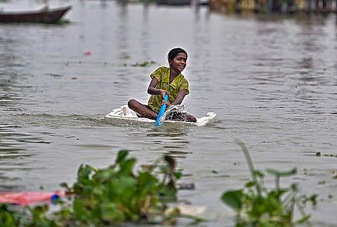 A girl uses a makeshift styrofoam raft to row through an inundated area following monsoon rains, in Prayagraj.
